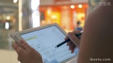 一个女人在机场或购物中心用平板电脑打字或做笔记的特写镜头